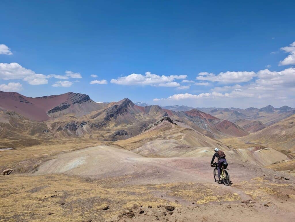 Bikepacker riding bike down faint trail in Andean mountains of Peru