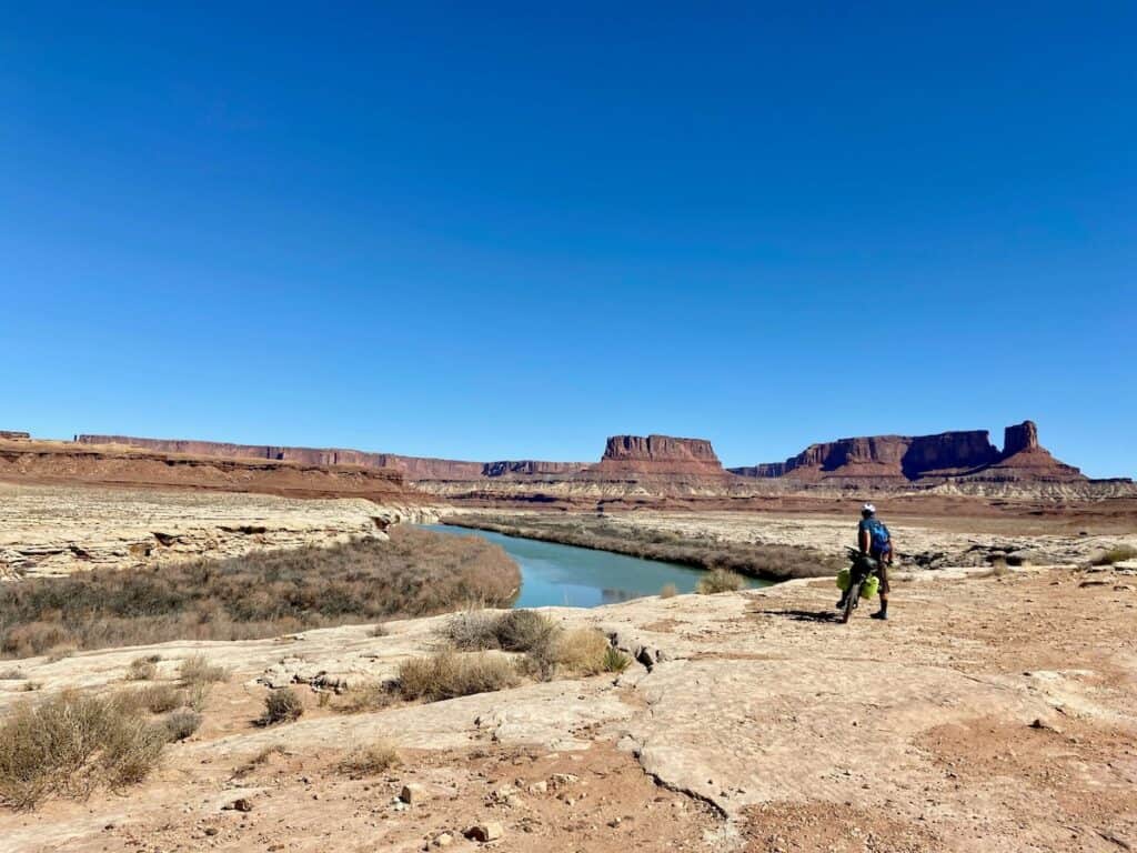 Mountain biker stopped to take in views over river in slickrock desert area of Utah