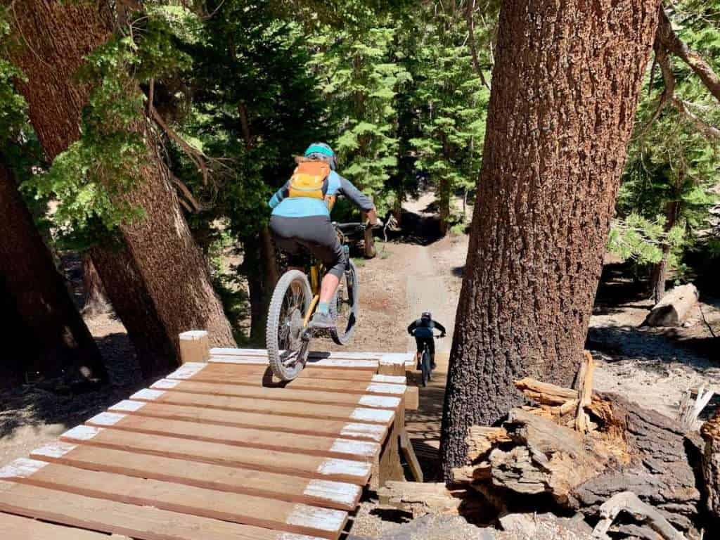 Becky riding off the wooden Flow Drop at Mammoth Bike Park