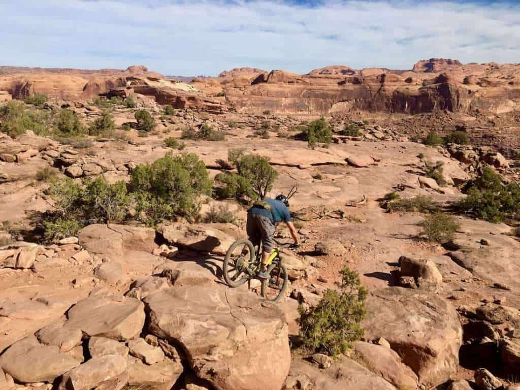 Mountain biker riding down technical section of rocky slickrock trail in Moab, Utah.