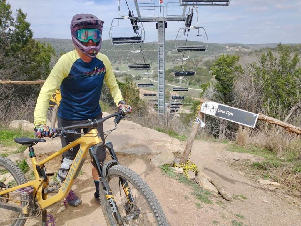 Mountain biker standing next to bike wearing full face helmet at Spider Mountain Bike Park in Texas