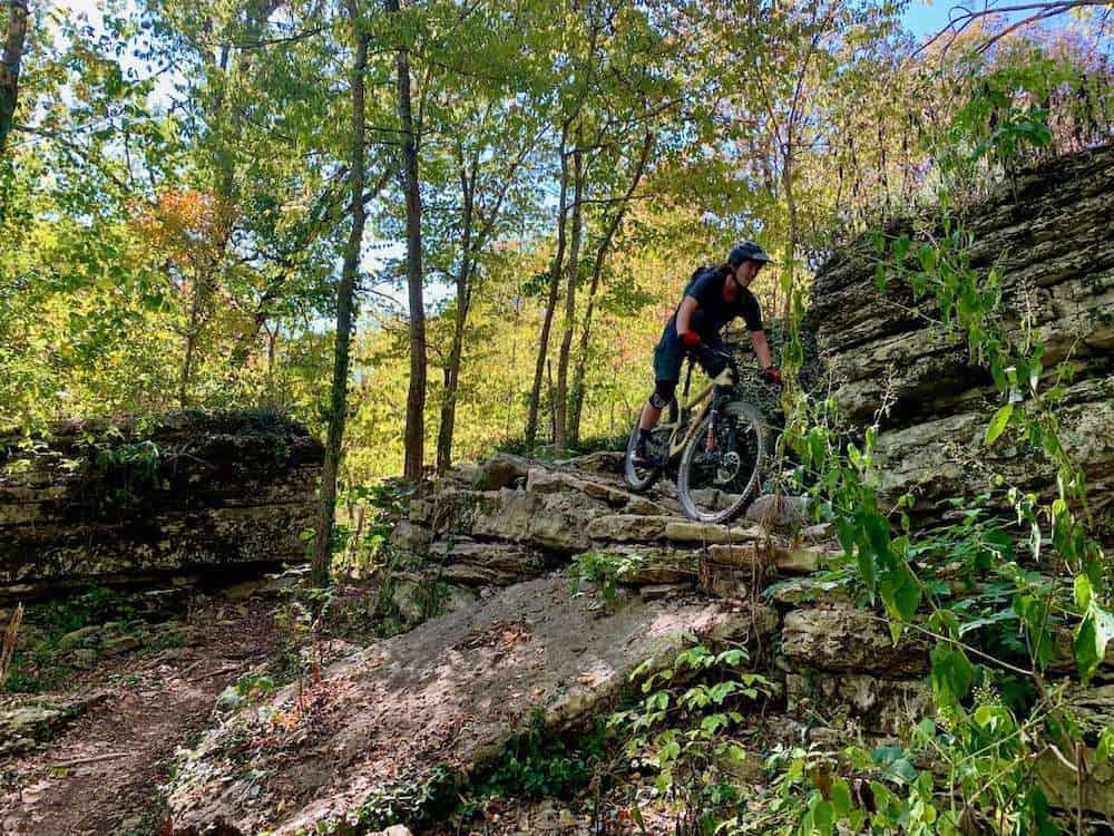 Becky riding rock ledge section of mountain bike trail in Bentonville, Arkansas