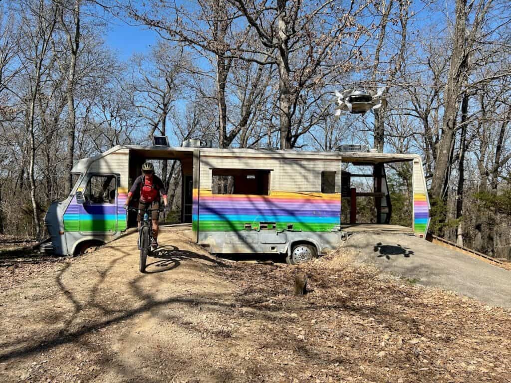 Mountain biker riding out of converted RV trail hub at the Alice in Wonderland Trails in Bentonville, Arkansas