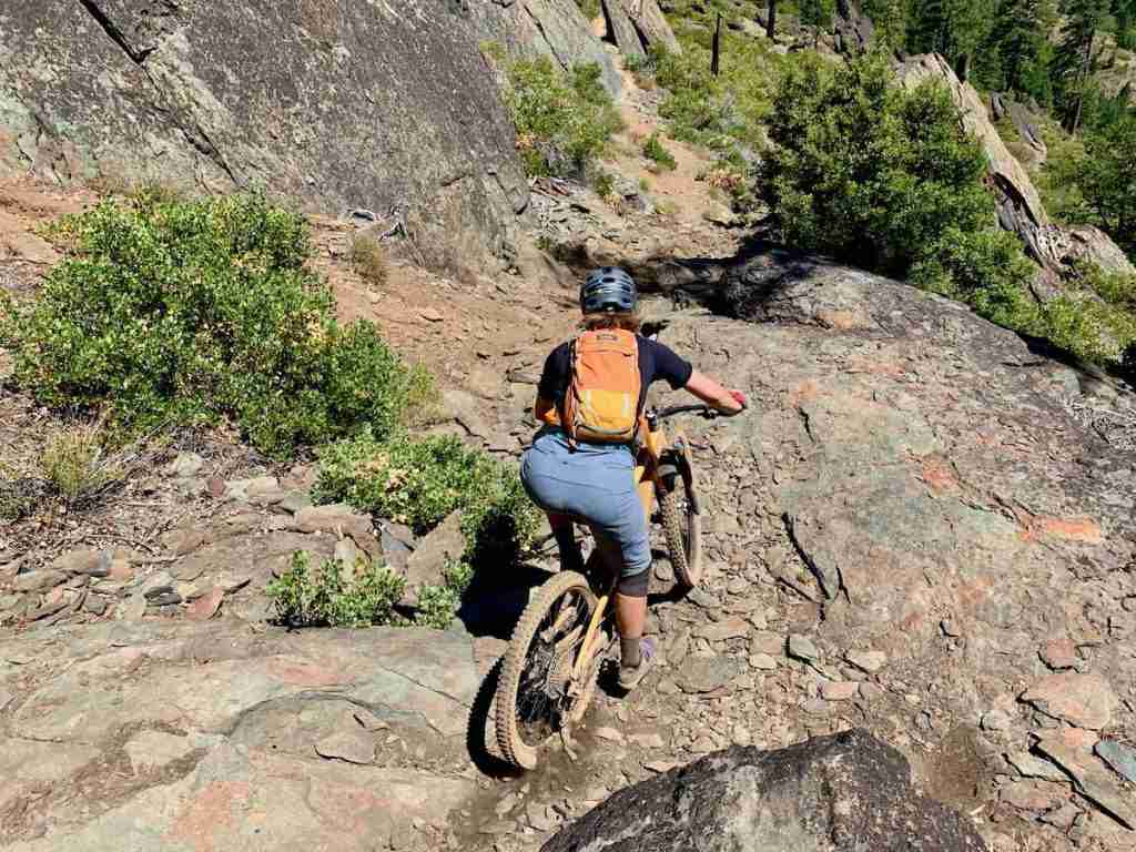 Mountain biker riding bike down rocky trail