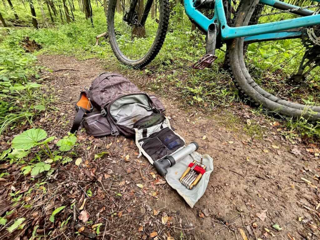 Mountain bike tools and backpack laid out on trail