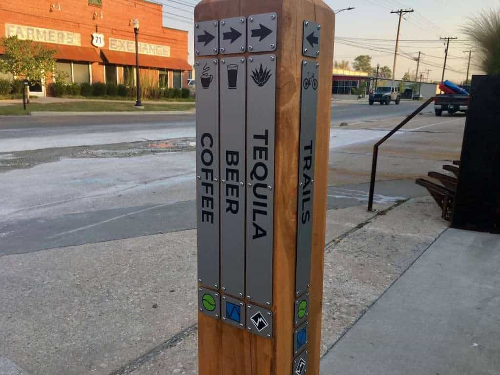 Sign post in Bentonville, Arkansas that reads Coffee, Beer, Tequila, and Trails with arrows pointing in different directions